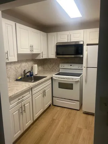 a kitchen with white cabinets and white appliances