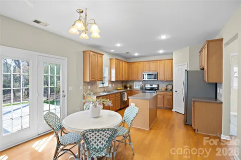 a dining room with stainless steel appliances kitchen island granite countertop a refrigerator a stove a sink dishwasher with a dining table and chairs with wooden floor