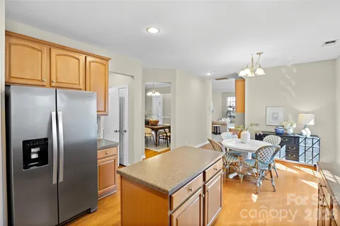 a kitchen with stainless steel appliances granite countertop a refrigerator a stove a sink a dining table and chairs with wooden floor