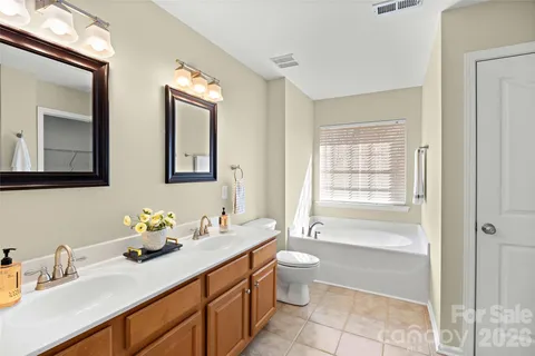 a bathroom with double vanity sinks a mirror and a bathtub