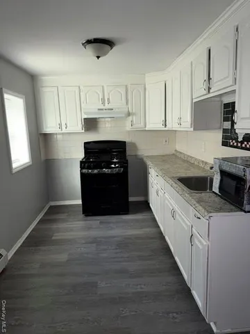 a kitchen with granite countertop a stove a sink and a refrigerator