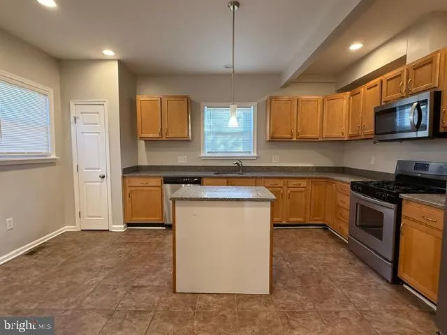 a kitchen with stainless steel appliances granite countertop a stove a sink and a refrigerator