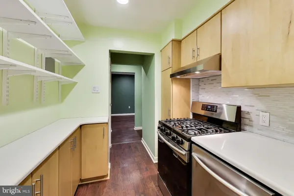 a kitchen with stainless steel appliances a stove a sink a refrigerator wooden floor and cabinets