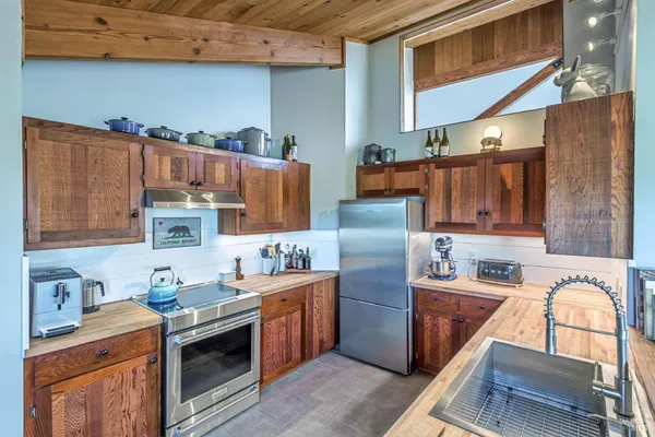 a kitchen that has a sink wooden cabinets and stainless steel appliances