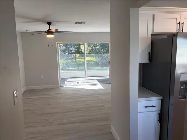 a view of empty room with wooden floor and fan