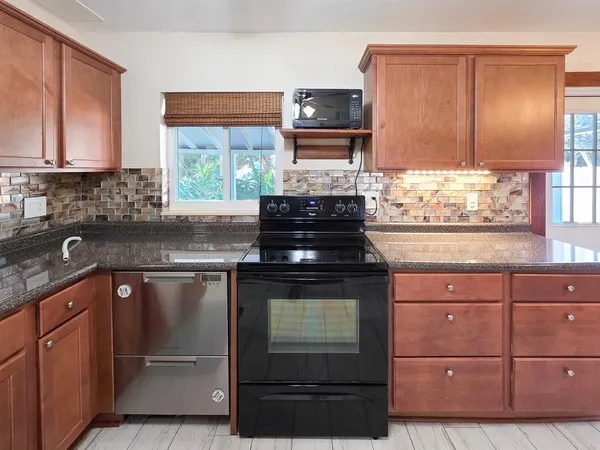 a kitchen with granite countertop a stove sink and cabinets