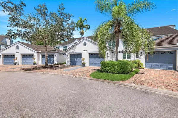 a view of a white house with a yard and palm trees