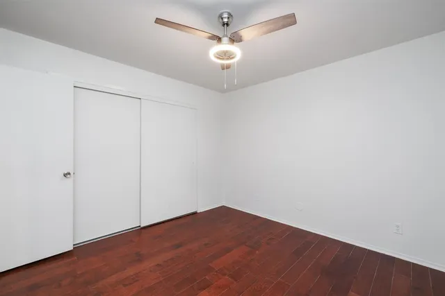 an empty room with wooden floor and fan