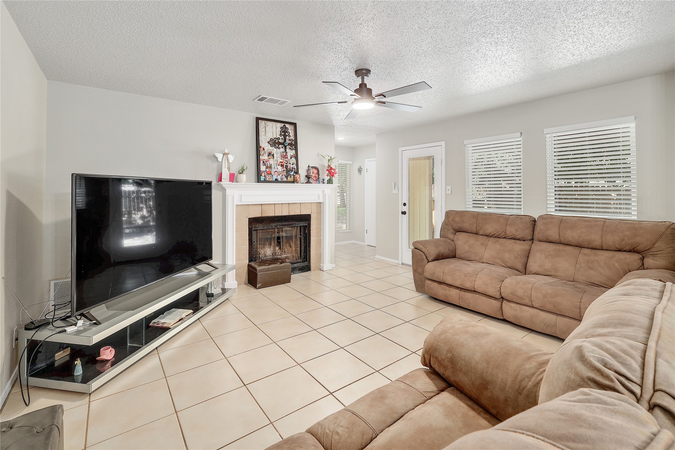 9906 Parliament House Road Austin, TX 78729 - Photo 5 of 33 Tiled flooring and a fireplace with a classic mantel define this welcoming living space.