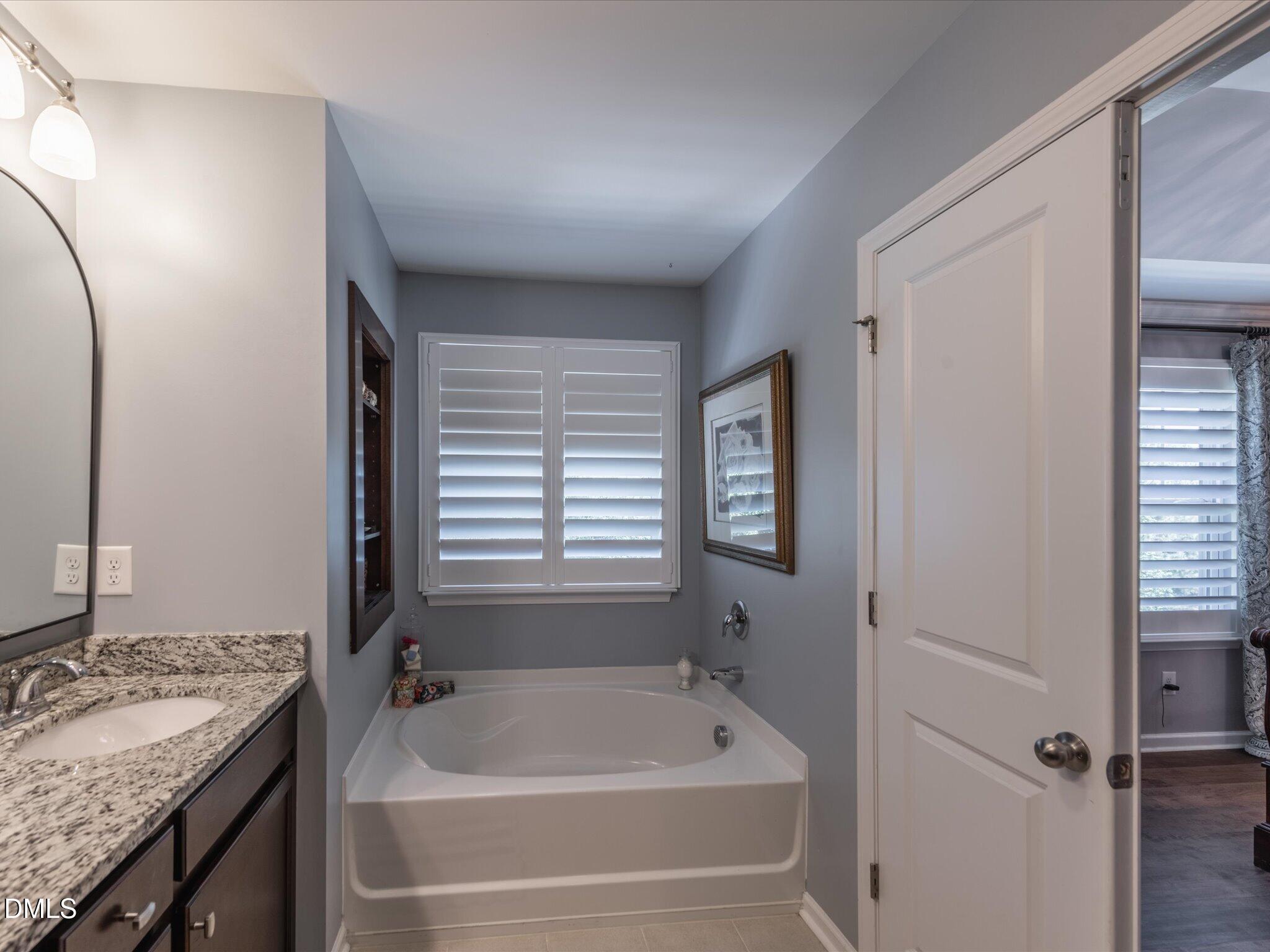 533 Metro Station Apex, NC 27502 - Photo 36 of 45 a bathroom with a granite countertop tub sink and mirror