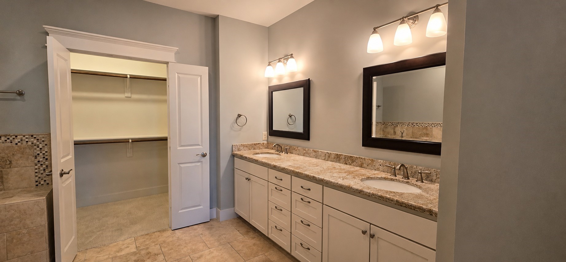 1117 Bonner Street Houston, TX 77007 - Photo 34 of 44 Primary bathroom features granite countertops with double sinks, each with their own framed mirrors and overhead lighting. Cabinets and drawers provide an abundance of storage options. Double doors open to the primary bedroom walk-in closet.