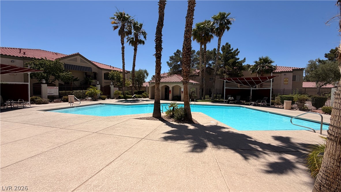 7885 West Flamingo Road, Unit 1131 Las Vegas, NV 89147 - Photo 5 of 36 An inviting community pool beckons under the clear sky, surrounded by palm trees and classic Mediterranean-style architecture.
