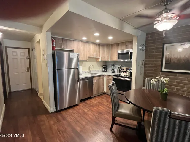 a kitchen with stainless steel appliances granite countertop a refrigerator a stove a sink dishwasher a dining table and chairs with wooden floor