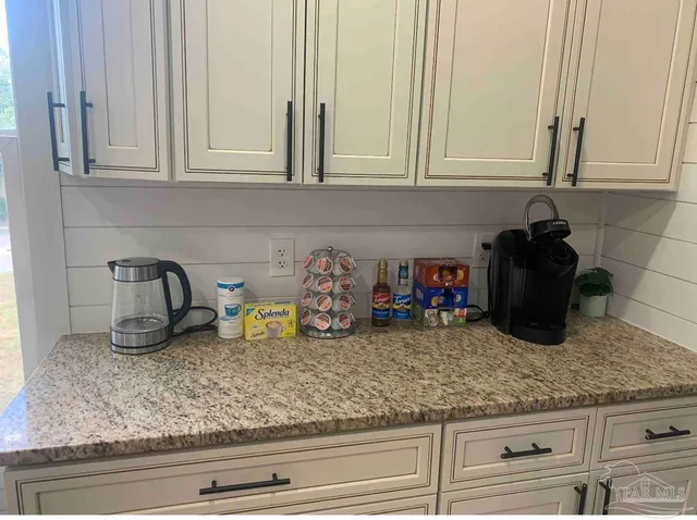 a kitchen with white cabinets and sink