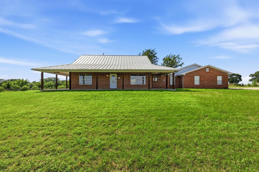 Brick exterior home featuring a metal roof and an expansive covered porch