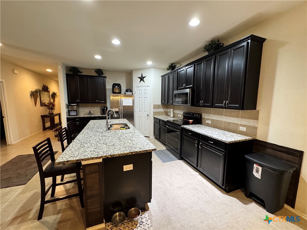 3101 Shawlands Road Killeen, TX 76542 - Photo 8 of 41 a kitchen with kitchen island granite countertop wooden cabinets and a refrigerator