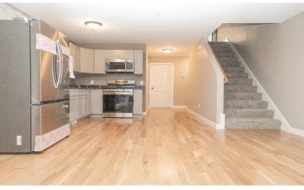a kitchen with granite countertop a refrigerator oven a sink and white cabinets