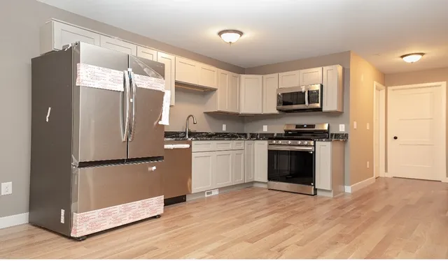 a kitchen with granite countertop a refrigerator and a stove top oven
