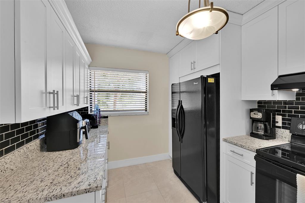 3591 Environ Boulevard, Unit A305 Lauderhill, FL 33319 - Photo 13 of 73 a kitchen with stainless steel appliances granite countertop a refrigerator a stove and a sink