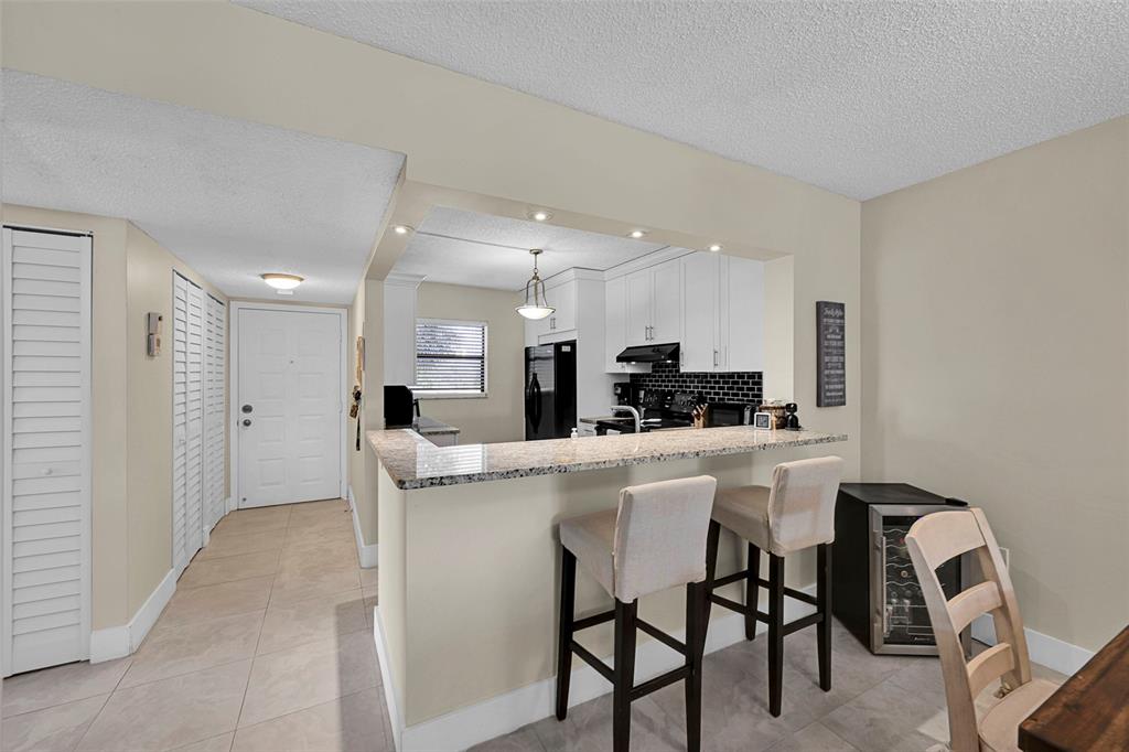 3591 Environ Boulevard, Unit A305 Lauderhill, FL 33319 - Photo 17 of 73 a kitchen with a dining table chairs and refrigerator
