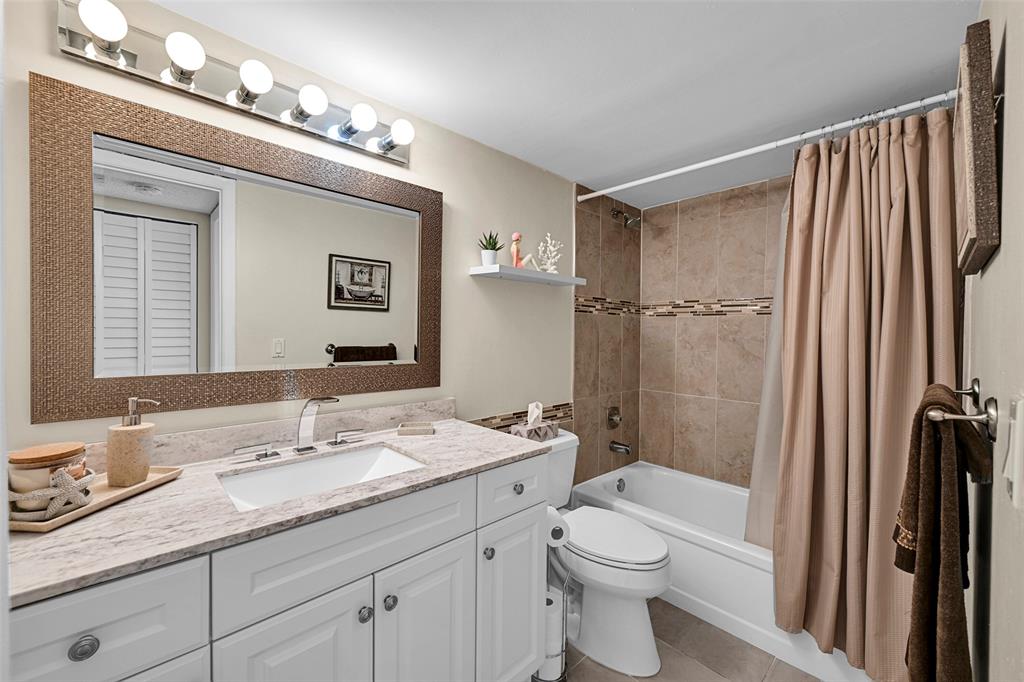 3591 Environ Boulevard, Unit A305 Lauderhill, FL 33319 - Photo 37 of 73 a bathroom with a granite countertop sink toilet a large mirror a shower and vanity