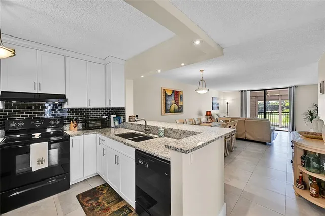 a kitchen with stainless steel appliances granite countertop a refrigerator a stove and a sink