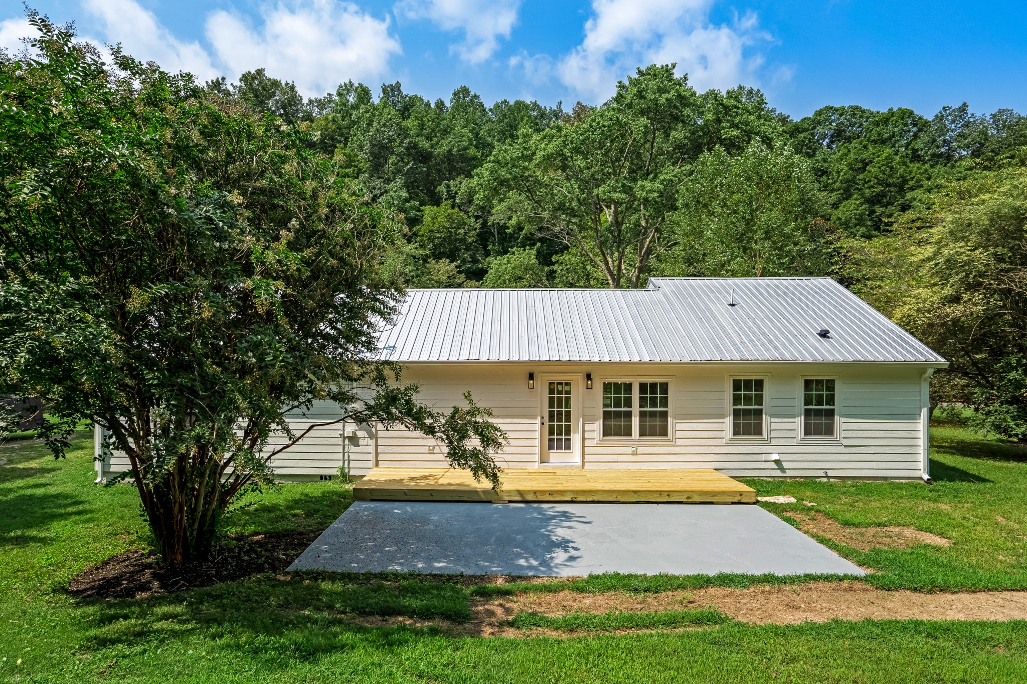 4048 Skelley Road Santa Fe, TN 38482 - Photo 34 of 43 a view of a white house with a swimming pool and lawn chairs under an umbrella