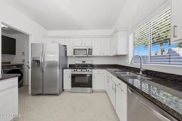 a kitchen with stainless steel appliances granite countertop a refrigerator a stove a sink and dishwasher