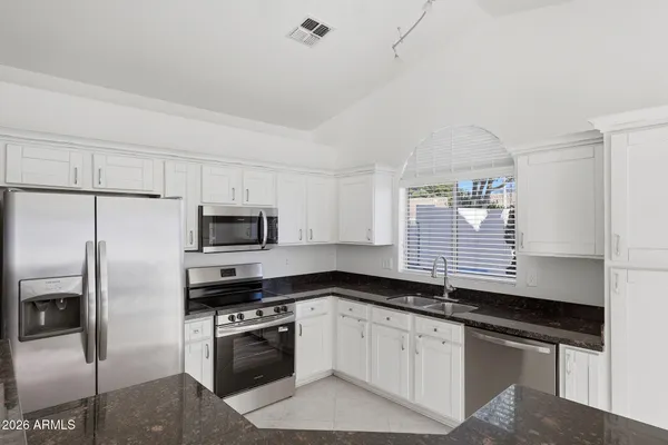 a kitchen with granite countertop a sink stove and refrigerator