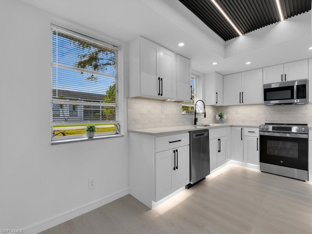 4941 Aztec Circle Naples, FL 34112 - Photo 11 of 36 a kitchen with stainless steel appliances granite countertop a stove a sink and a refrigerator