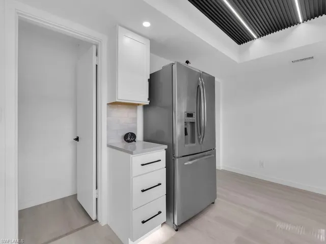 an empty room with a chandelier fan and wooden floor