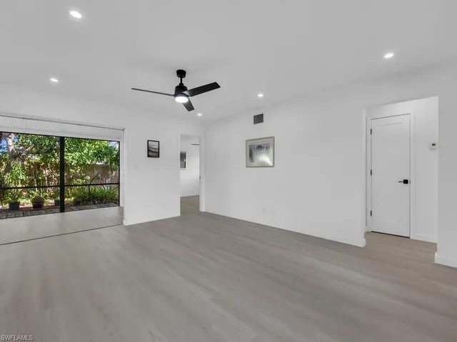 an empty room with ceiling fan and windows