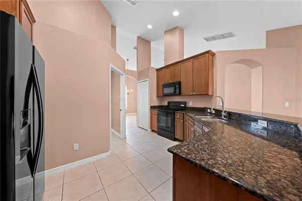 a kitchen with stainless steel appliances granite countertop a refrigerator a stove a sink and a microwave