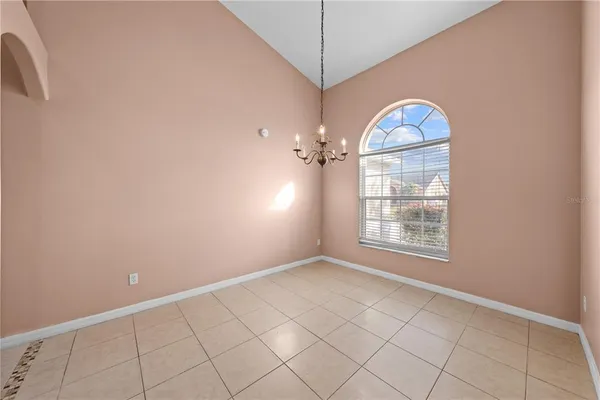 an empty room with chandelier fan and windows