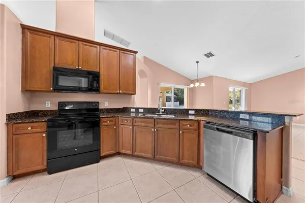 a kitchen with stainless steel appliances granite countertop a stove top oven a sink dishwasher and a microwave oven on the blue kitchen countertops