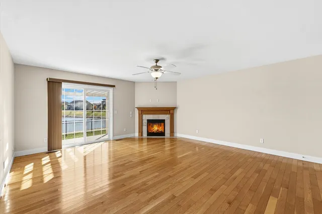 a view of an empty room with wooden floor fireplace and a window