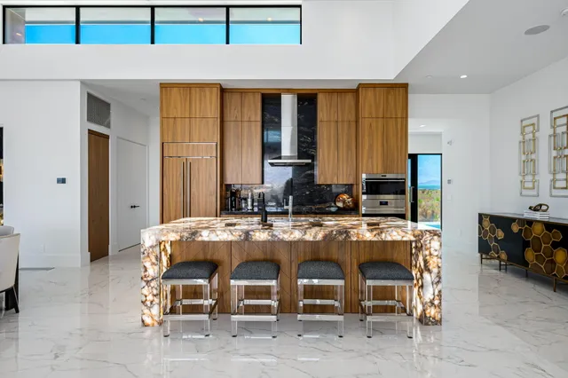 a view of a kitchen with kitchen island granite countertop a large window cabinets and stainless steel appliances