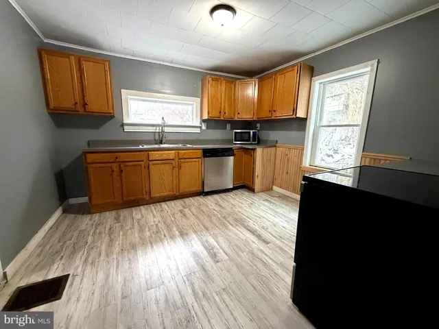 a kitchen with granite countertop wooden floors a sink a window and appliances