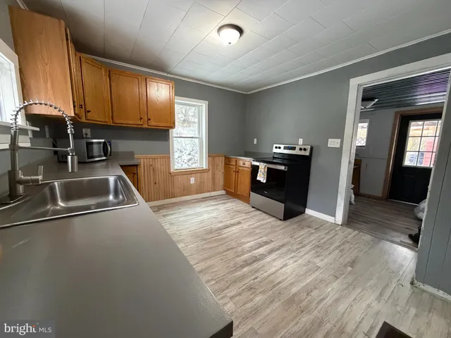 a kitchen with stainless steel appliances granite countertop a refrigerator a sink dishwasher a stove and white countertops with wooden floor