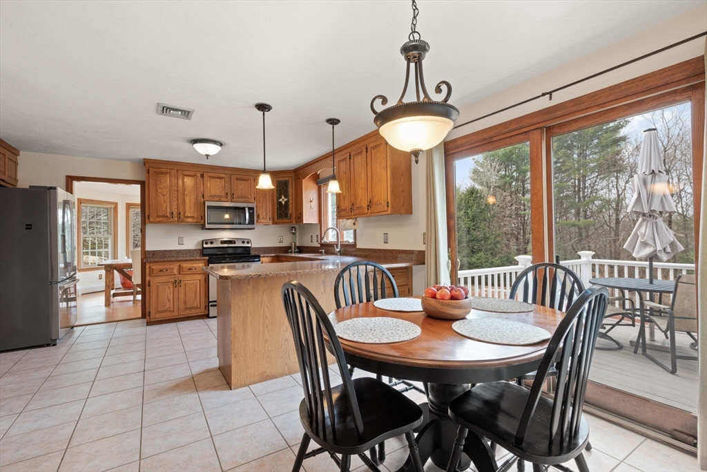 3 Daniels Road Mendon, MA 01756 - Photo 16 of 42 a kitchen with stainless steel appliances granite countertop a stove a refrigerator a kitchen island a table and chairs with wooden floor