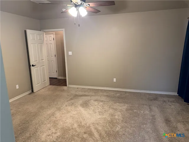 a view of an empty room with a chandelier fan