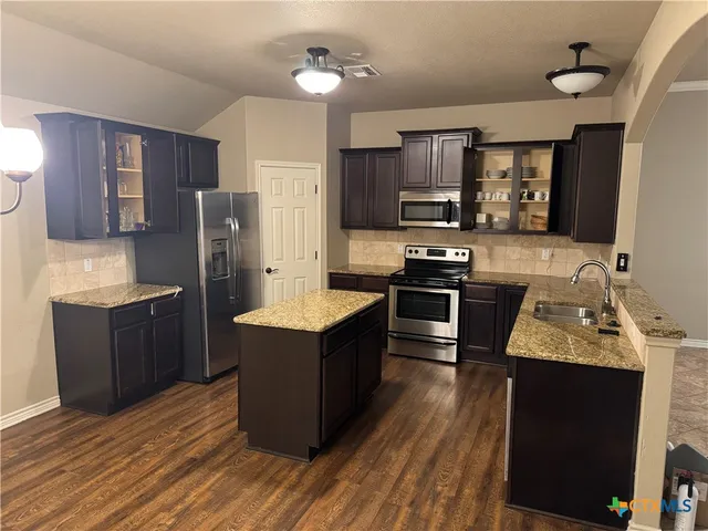 a kitchen with stainless steel appliances granite countertop a refrigerator stove and sink