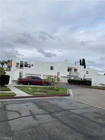 a view of a white house with a big yard and potted plants