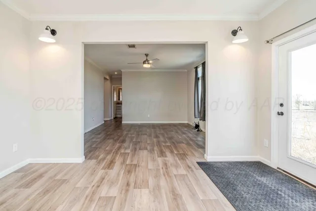 a view of an empty room with window and wooden floor