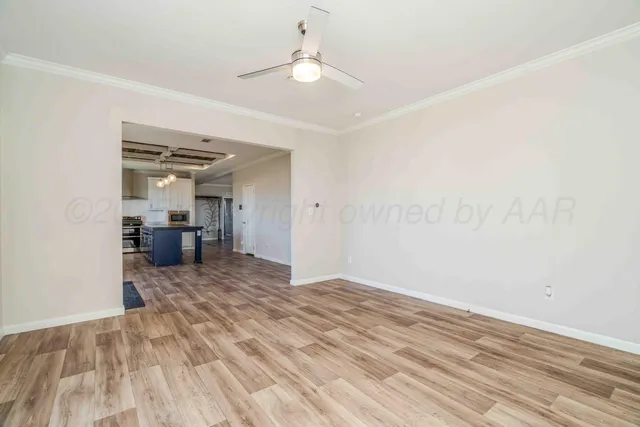 an empty room with a chandelier fan and windows