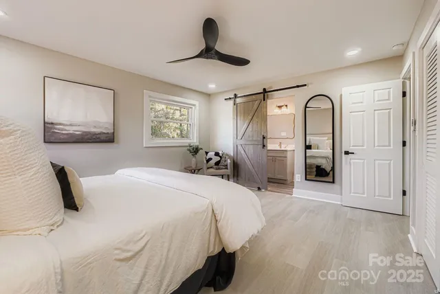 a bedroom with a bed large mirror and window