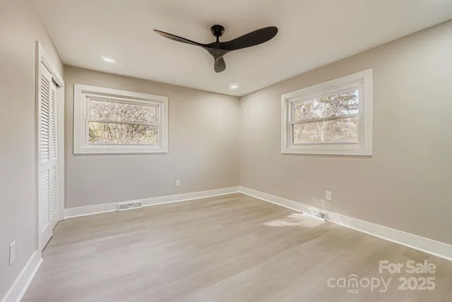 an empty room with wooden floor and ceiling fan
