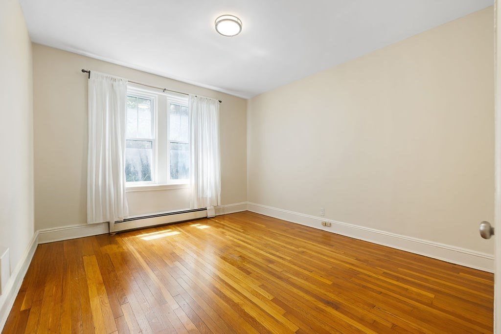321 Tappan Street, Unit 2 Brookline, MA 02445 - Photo 13 of 25 an empty room with wooden floor and windows