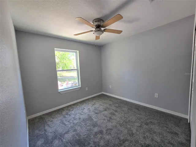 an empty room with a window and a ceiling fan