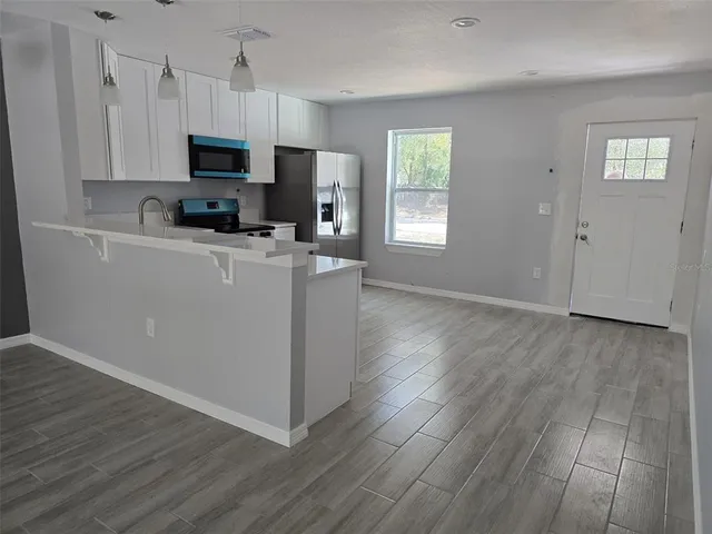 a view of a kitchen with wooden floor and electronic appliances